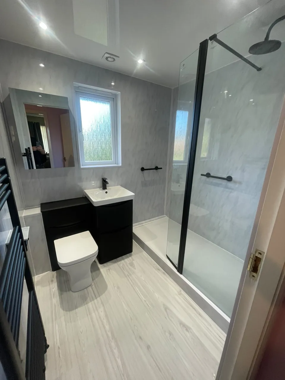 Black vanity and glass shower screen with pale walls