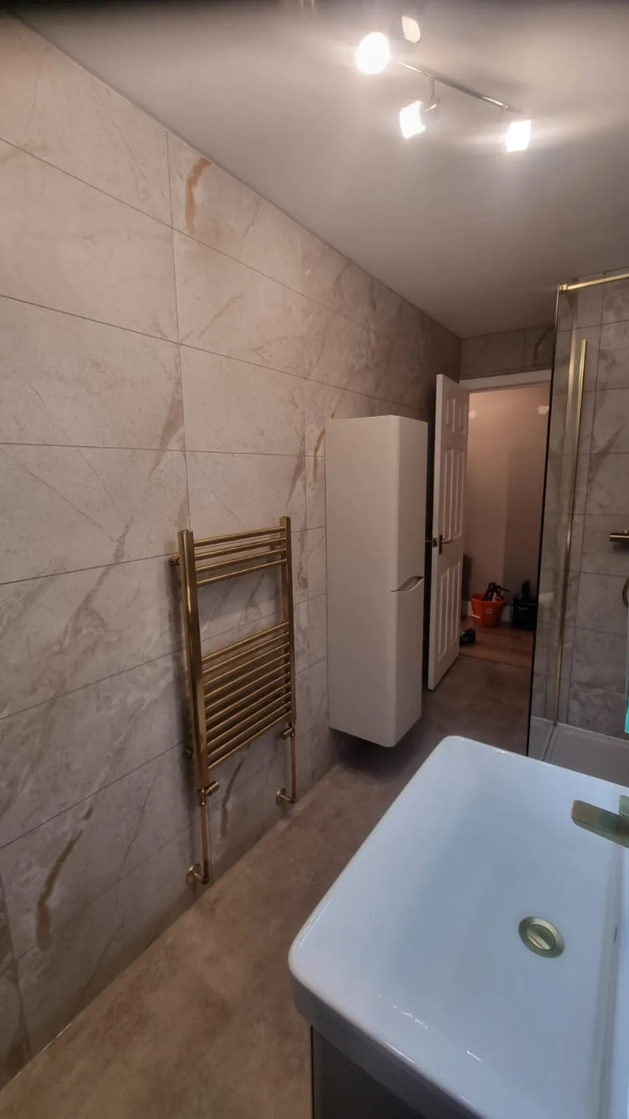Basin, towel rail and tall storage in a narrow bathroom